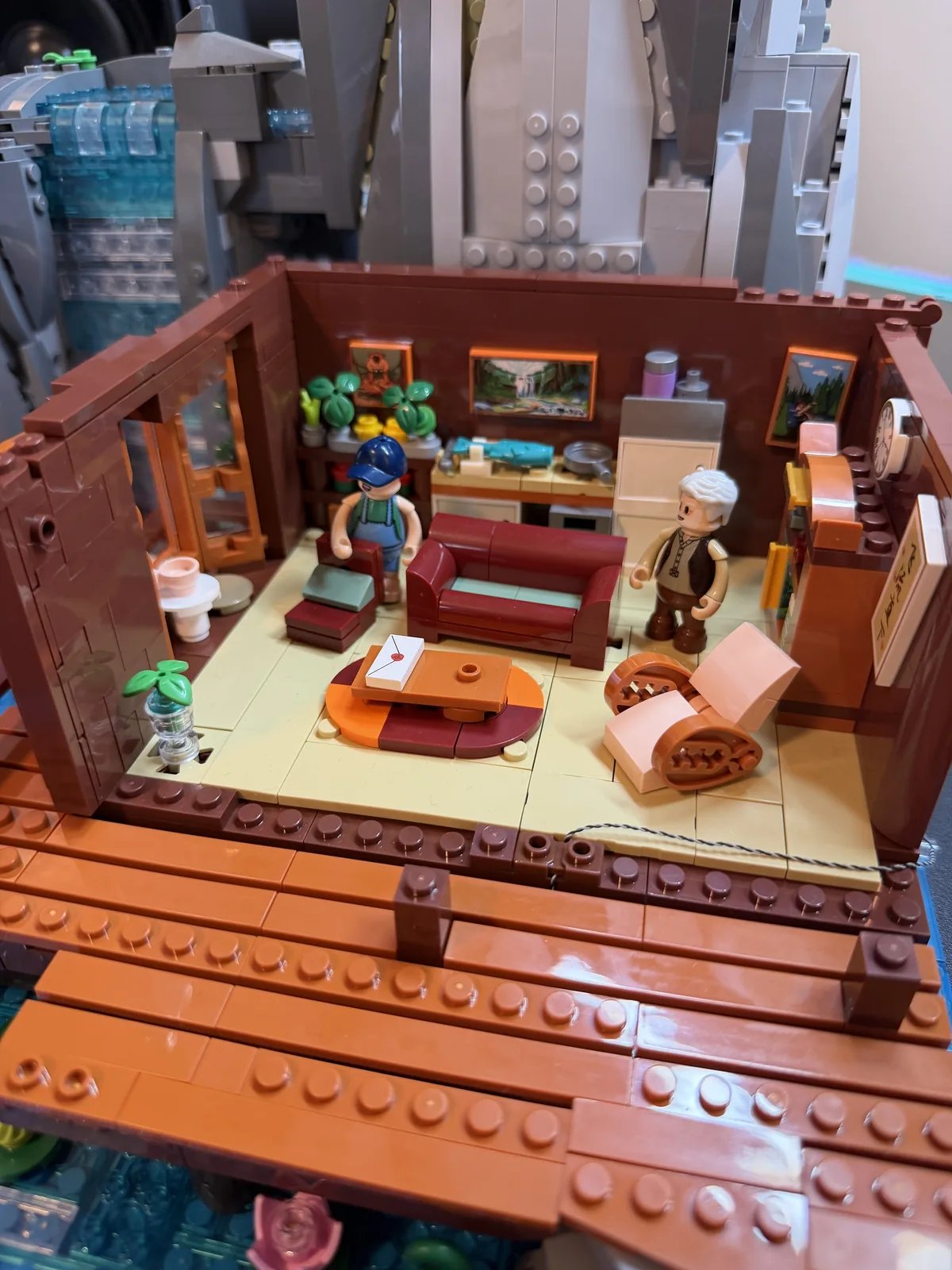 Lumibricks 10010 Waterfall Cabin — first-floor interior with both minifigures, sofa, rocking chair and kitchen