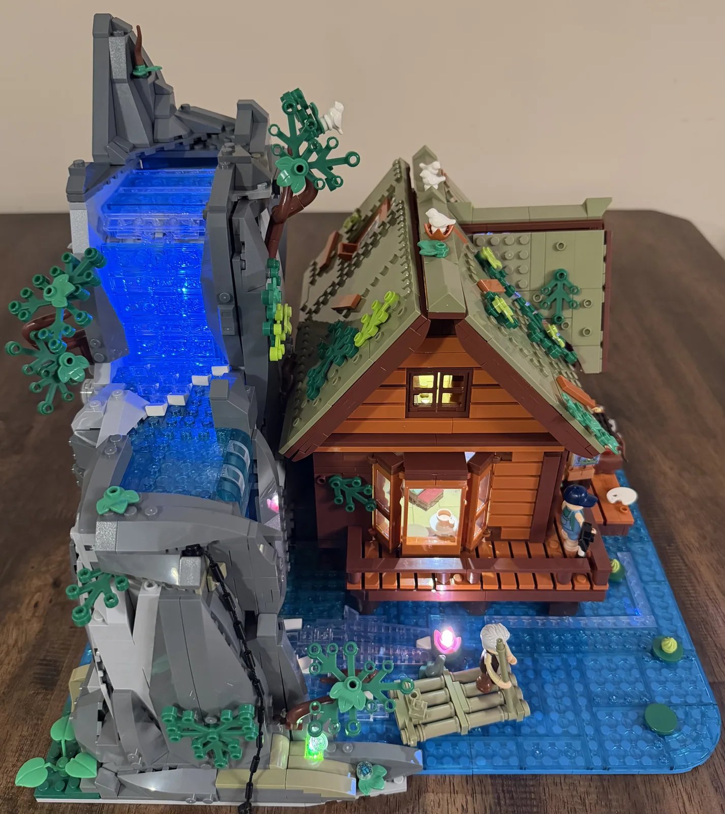 Lumibricks 10010 Waterfall Cabin — finished build three-quarter view with blue waterfall LEDs on