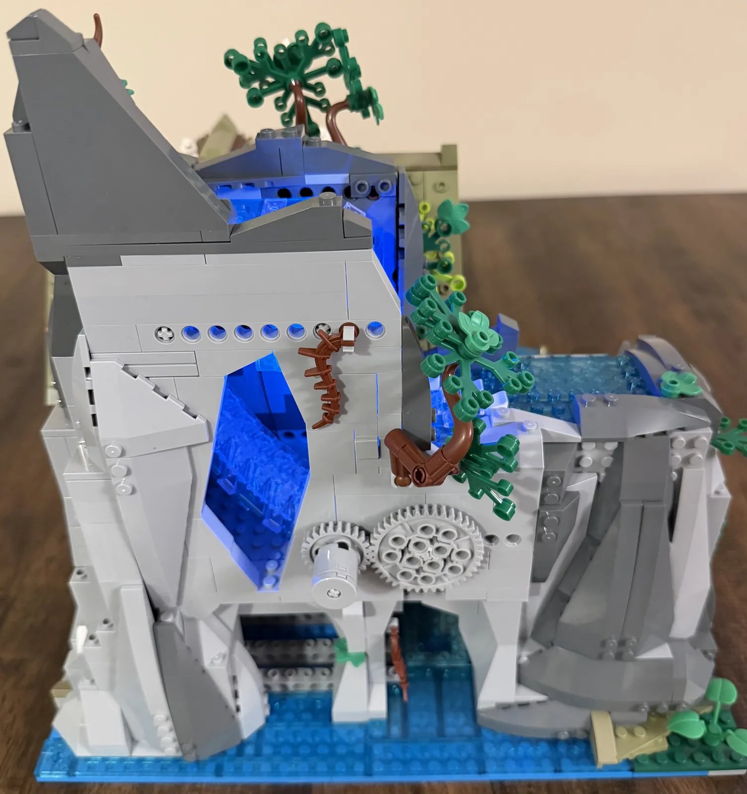 Lumibricks 10010 Waterfall Cabin — mountain side showing gears and the lit waterfall channel