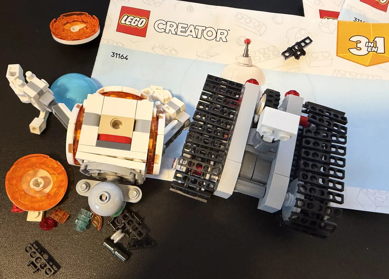 LEGO 31164 Creator 3-in-1 Space Robot — parts and partially built sections laid out next to the instruction booklet
