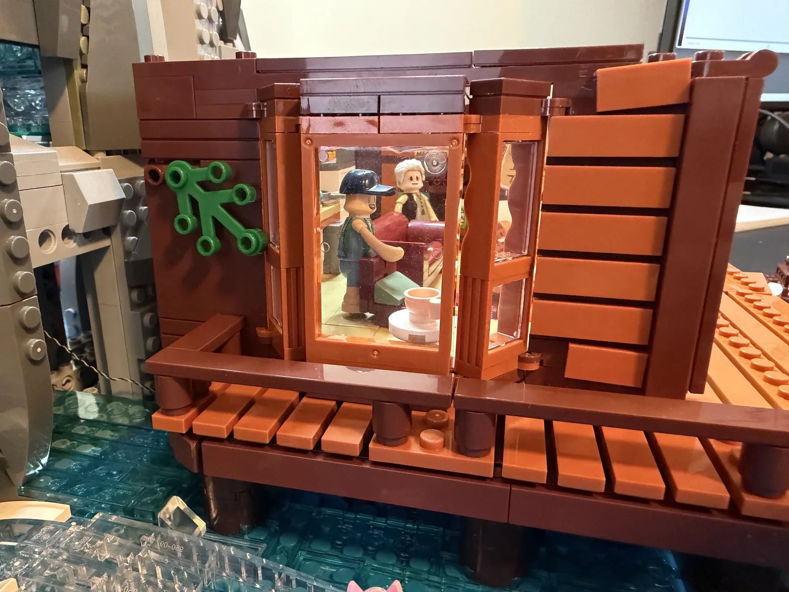 Lumibricks 10010 Waterfall Cabin — bay window view into the first-floor living room from the deck