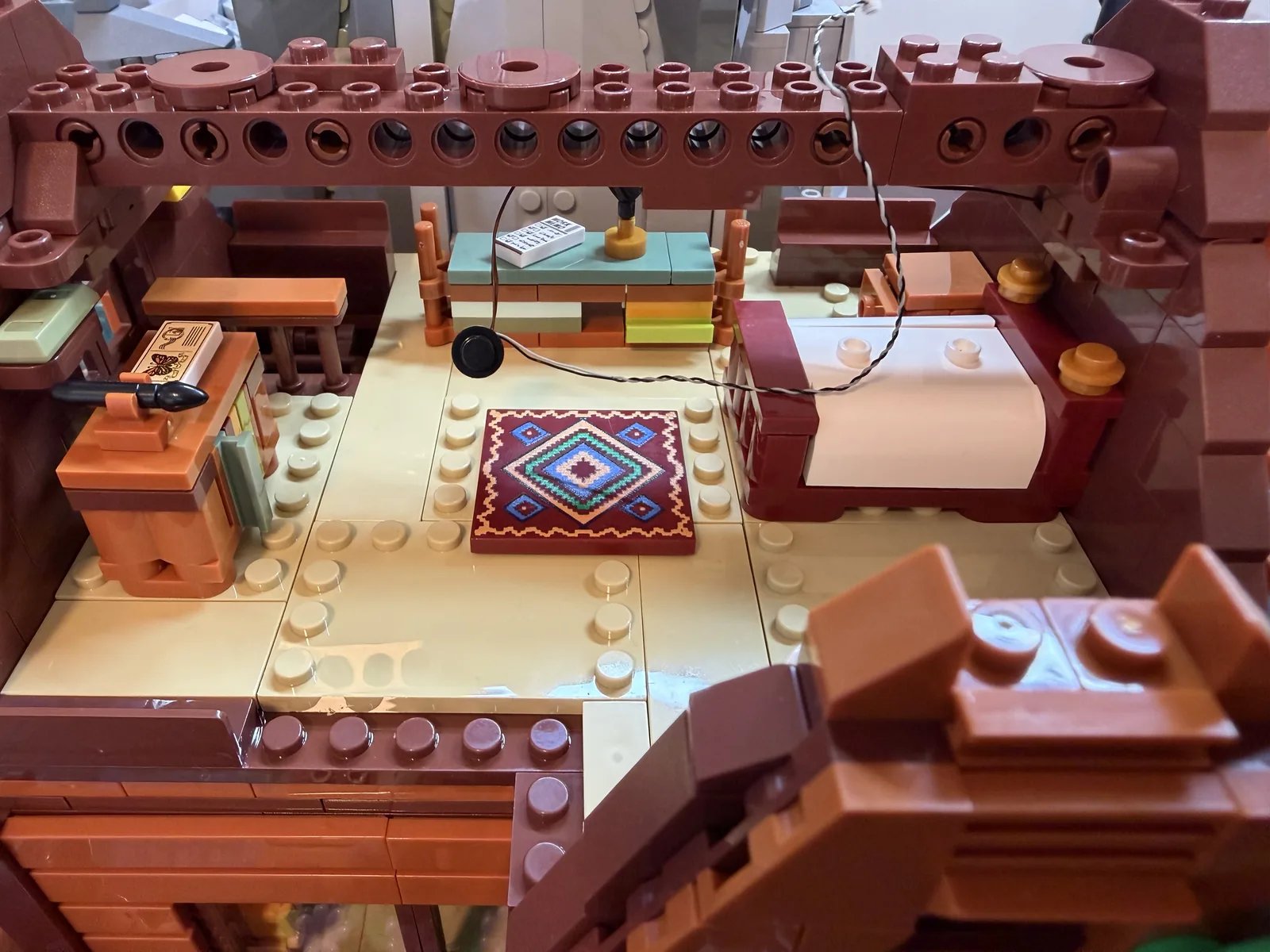 Lumibricks 10010 Waterfall Cabin — second-floor bedroom with hanging LED light over the patterned rug