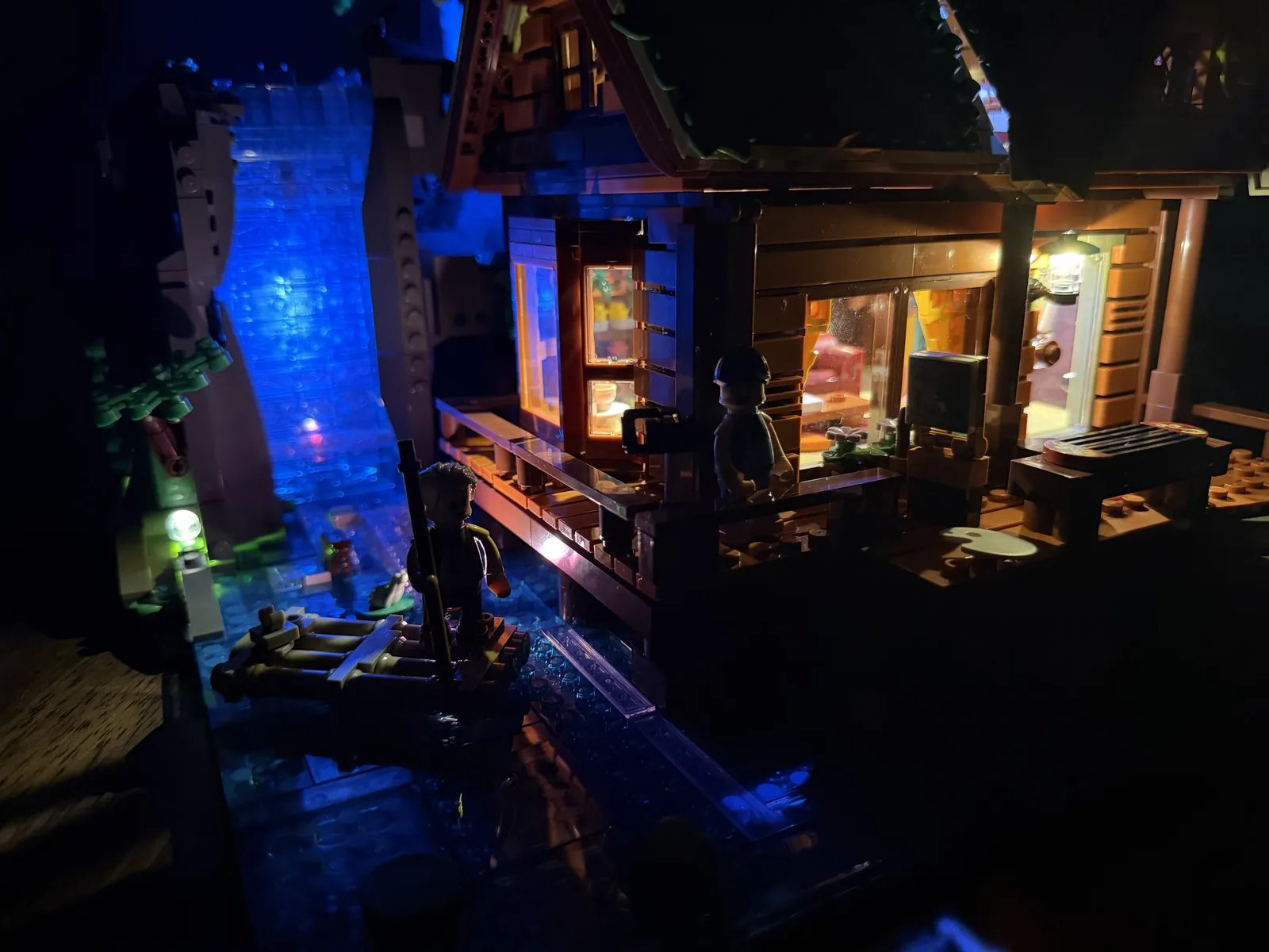 Lumibricks 10010 Waterfall Cabin — night display with warm cabin windows and blue waterfall