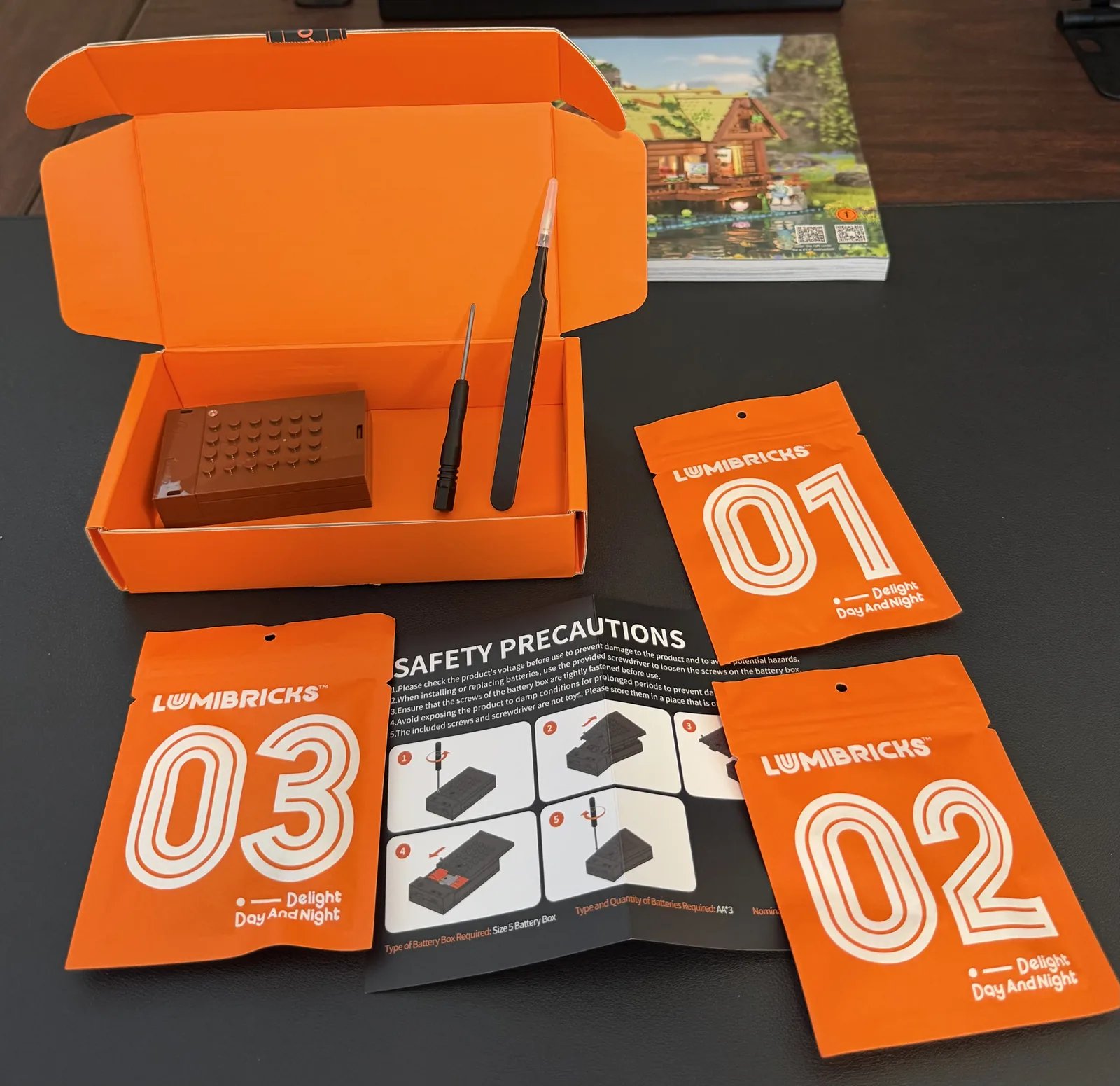 Lumibricks 10010 Waterfall Cabin — orange lighting kit box with LED pouches, battery box, tweezers and screwdriver